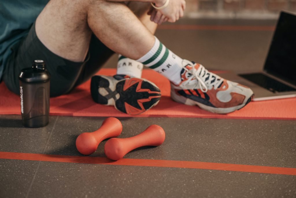 person on gym mat with weights following strength exercise